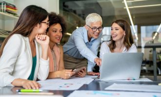 Smiling diverse colleagues gather in boardroom brainstorm discuss financial statistics together, happy multiracial coworkers have fun cooperating working together at office meeting, teamwork concept