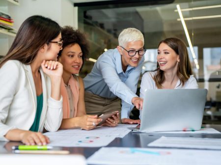 Smiling diverse colleagues gather in boardroom brainstorm discuss financial statistics together Smiling diverse colleagues gather in boardroom brainstorm discuss financial statistics together, happy multiracial coworkers have fun cooperating working together at office meeting, teamwork concept