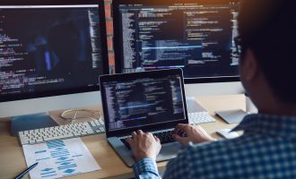 Rear view of software developers is sitting serious analyzing data on the computer screen.